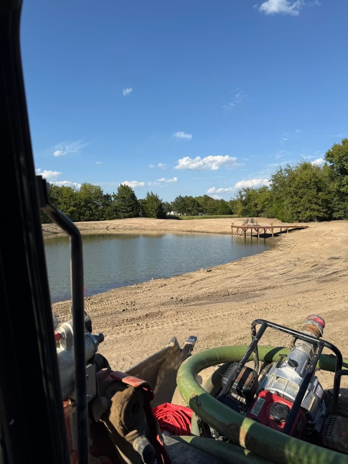 Pond with fresh dirt work and a new dock, seen from the machine